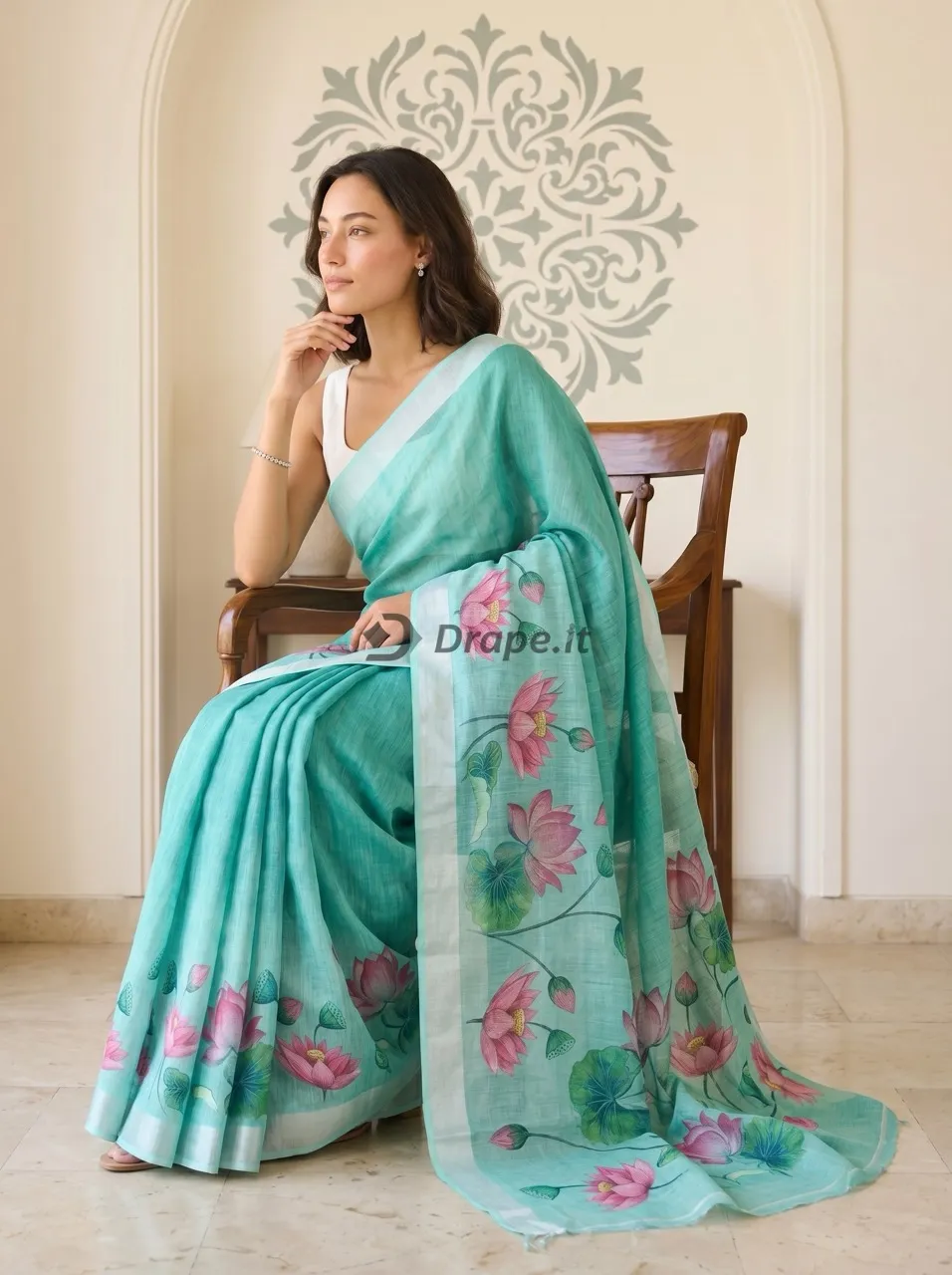 Seated model photoshoot pose in a turquoise linen saree with lotus floral pallu